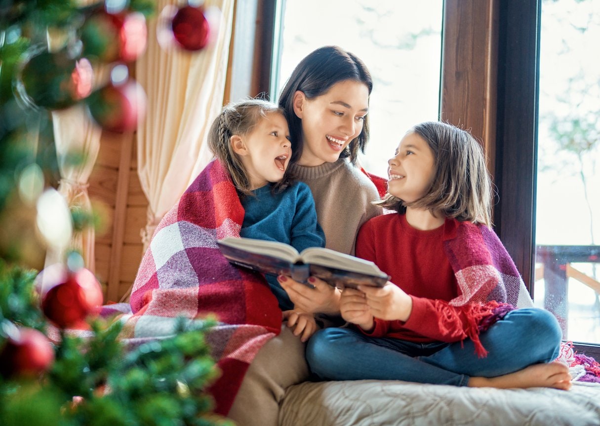 woman sitting with two young girls reading a book