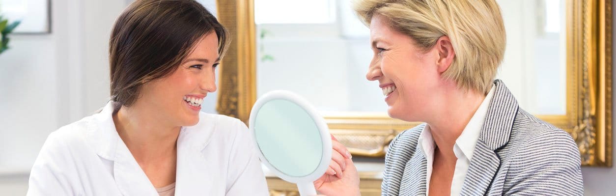 Doctor and patient smiling and looking in mirror