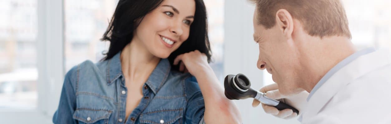 dermatologist doing skin exam on female patient's arm